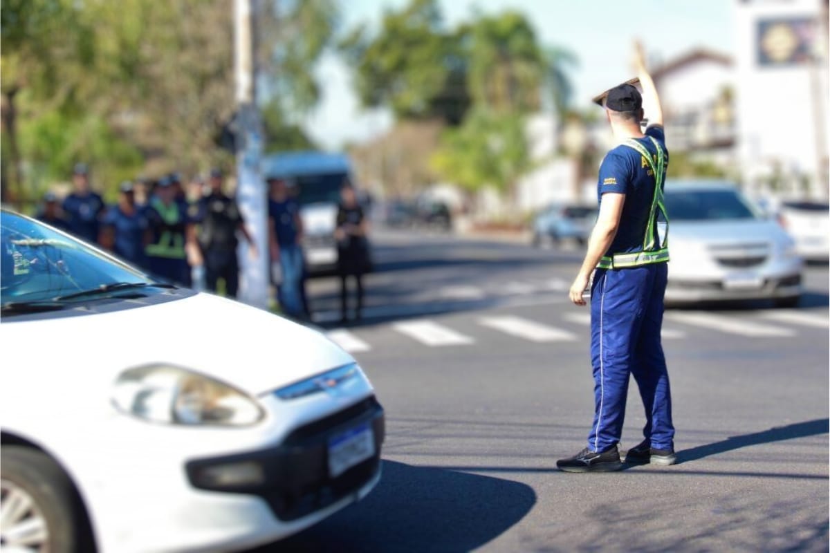 Agente de trânsito orientando veículos em cruzamento.