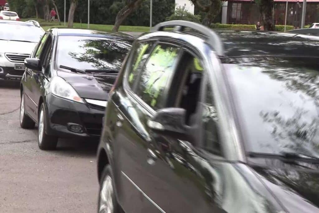 Carros estacionados ao longo de uma rua arborizada.