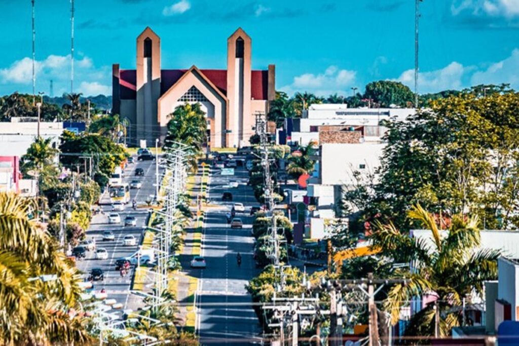 Avenida movimentada com igreja ao fundo.