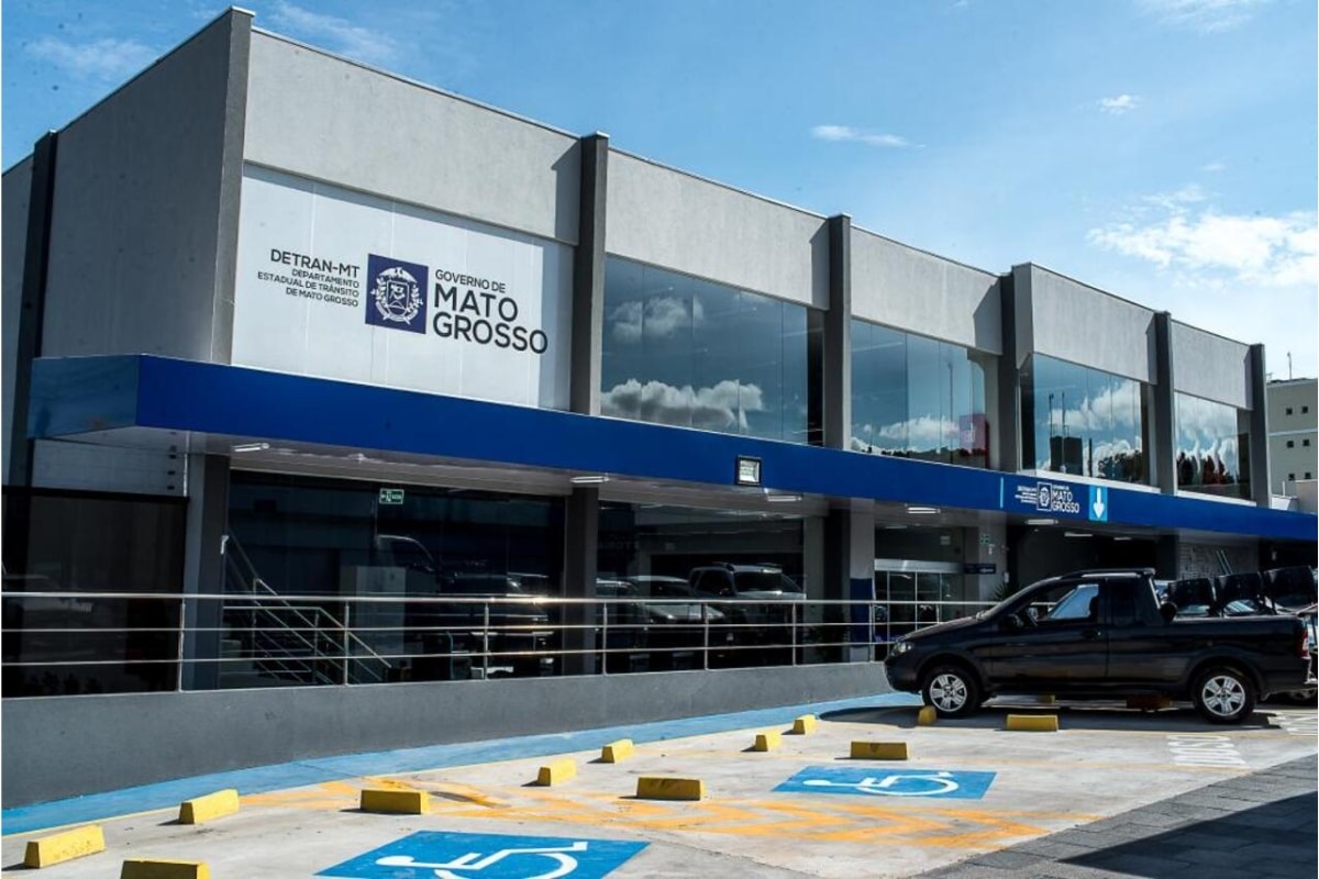Fachada do Detran-MT com estacionamento e céu azul.