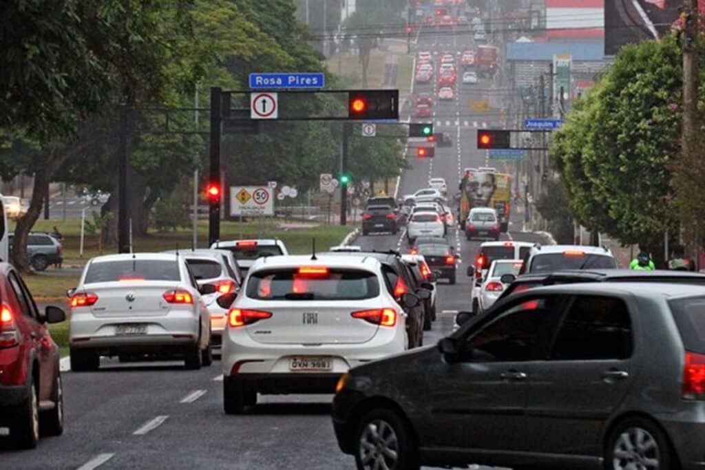 Trânsito intenso em avenida urbana chuvosa.